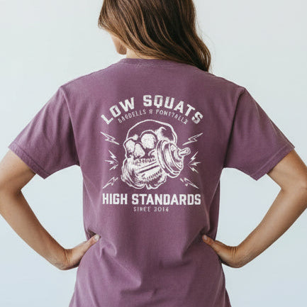 Person wearing a purple t-shirt with text and graphics, standing against a plain background